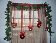 christmas decorations are hanging on the window sill in front of a sheered curtain