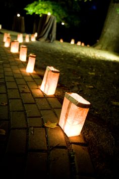 some paper bags sitting on the ground with lights around them and one bag in the middle