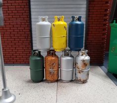 several different colored propane gas bottles lined up