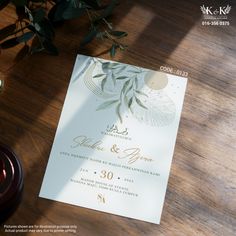 the wedding card is on top of a table next to a candle and some flowers