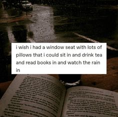 an open book sitting on top of a wooden table next to a rain soaked street