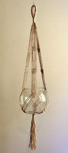 a hanging glass bowl with tassels on the bottom and roped around it