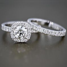 two wedding rings with diamonds on them sitting on a gray surface in front of the camera