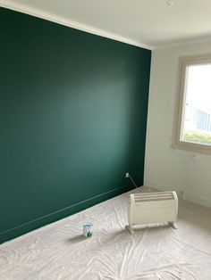 an empty room with green walls and white sheets on the floor next to a radiator