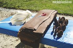 there is a cloth and scissors on top of a blue mat in the sand near some grass