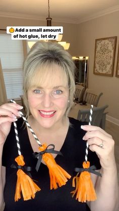 a woman holding two orange tassels in front of her face with the caption, add a small amount of hot glue, let dry