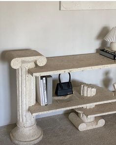 a book shelf with books and a purse on it next to a lamp in a room