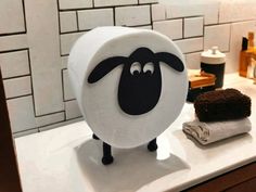 a black and white sheep standing on top of a counter next to a brown cake