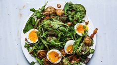 a white plate topped with an egg and spinach salad