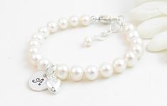 "Personalized real pearl bracelet for infant, baby or little girl: Created with gorgeous Grade-A round 5.5mm freshwater pearls, a durable sterling silver heart-shaped lobster clasp with a 1/2\" \"Grow with Me\" extender chain, a high quality 3/8\" round disc with one initial (4 font options to choose from), and a small sterling silver heart charm.  A small sparkling clear Swarovski® crystal is in between the two charms.  The charms can be placed front/center or near the clasp.  The pearls are st Elegant Hypoallergenic Name Bracelet With Round Beads, Elegant Hypoallergenic Bracelets For Birthday, Classic White Heart-shaped Bracelet, Hypoallergenic Pearl Bracelet For Birthday, Personalized Pearl Bracelet With Round Beads For Birthday, Personalized Pearl Bracelet For Birthday, Personalized Round Beads Pearl Bracelet For Birthday, Adjustable Hypoallergenic Pearl Bracelet For Birthday, Hypoallergenic Adjustable Pearl Bracelet For Birthday