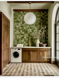 a washer and dryer in a room with green tiles on the wall behind it