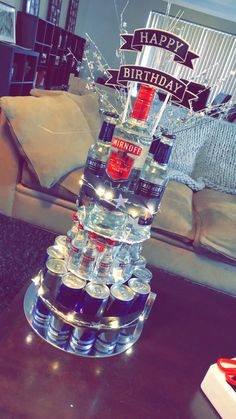 a birthday cake made out of liquor bottles on top of a table in a living room