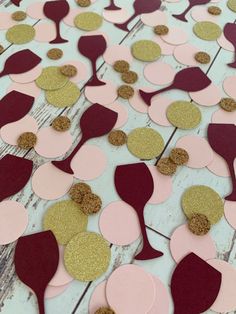 some pink and gold confetti pieces on a white wooden table with brown circles