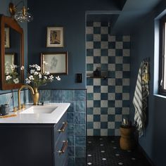 a bathroom with blue walls and checkered tile on the floor, along with white flowers