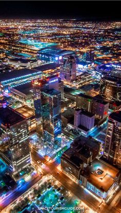 an aerial view of a city at night with lots of lights on the buildings and streets