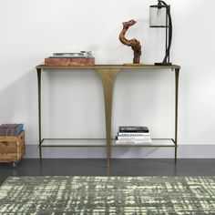 a table with a lamp and books on it in front of a wall mounted book shelf