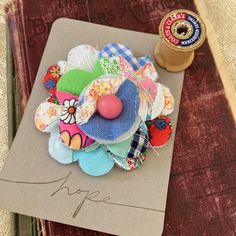 a bunch of fabric flowers sitting on top of a piece of paper next to a spool of thread