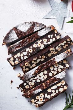 slices of chocolate and almond brownies on a white surface next to flowers, napkins and utensils