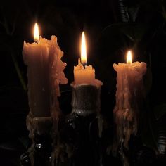 three candles are lit in the dark, with one candle on top of the other