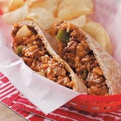 a close up of a sandwich and chips in a basket on a table with red and white checkered napkins