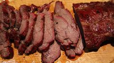 sliced meat sitting on top of a wooden cutting board