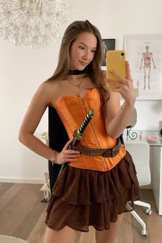 a woman in an orange corset taking a selfie with her cell phone