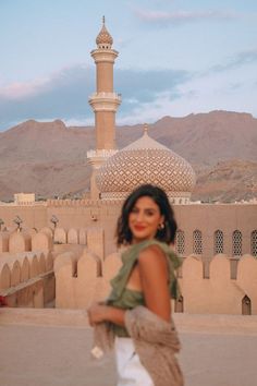 a woman standing in front of a building with a large dome on it's roof