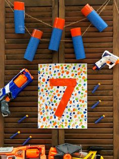 the number seven is made out of construction toys and paper streamers on a wooden slatted background