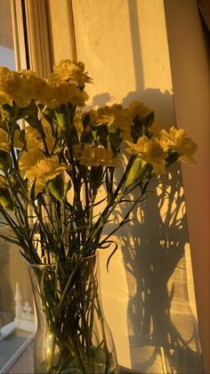 a vase filled with yellow flowers sitting on top of a window sill