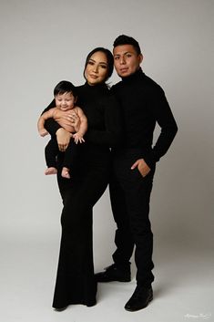 two men and a woman are posing for a photo with a baby in their arms