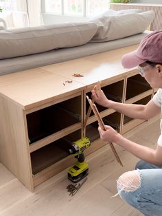 a woman is sitting on the floor working with some woodworking tools in her living room