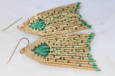 Handmade artisan boho chandelier earrings in the most gorgeous shades of emerald green and gold with gently swaying fringe. Each tiny bead is selected and hand sewn into place, one at a time with a needle and thread. No plastics, no glue, no looms - completely hand stitched with strong nylon thread.Ear wires are gold filled.Lightweight and comfortable, these earrings make a great gift or stocking stuffer for that special woman or a treat for yourself. All our items ship boxed and ready to gift. Green Dangle Beaded Earrings With Gold Beads, Bohemian Green Chandelier Earrings For Festive Occasions, Bohemian Green Earrings With Gold Beads, Unique Green Beaded Earrings For Party, Unique Green Beaded Party Earrings, Green Beaded Dangle Earrings For Festive Occasions, Unique Green Beaded Dangling Earrings, Handmade Green Bohemian Tassel Earrings, Festive Green Dangle Chandelier Earrings