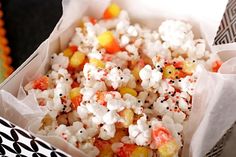 a bowl filled with popcorn and sprinkles on top of a black table