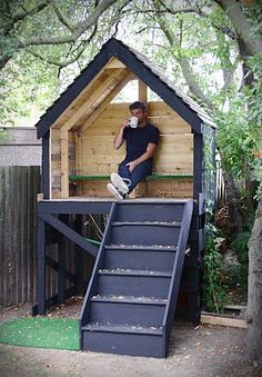 a man sitting on top of a wooden structure next to a stair case and tree