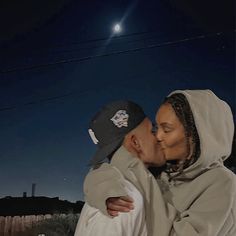 a man and woman kissing in front of the moon