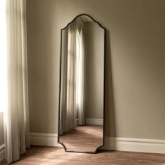 a large mirror sitting on top of a hard wood floor next to a white wall