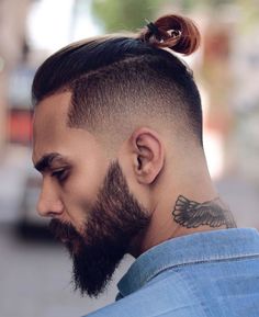 a man with a top knot undercut and a bald fade hair styled into a ponytail