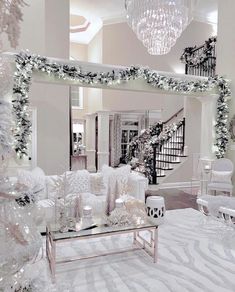 a living room decorated for christmas with white furniture and decorations on the walls, chandelier