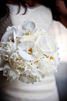 the bride's bouquet is white and has large flowers on it, including orchids