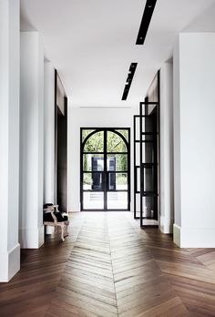 an empty hallway with wooden floors and black doors