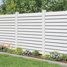 a white fence with flowers in the foreground and grass on the ground next to it