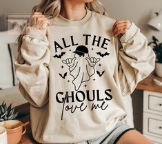 a woman wearing a sweatshirt that says all the ghouls love me