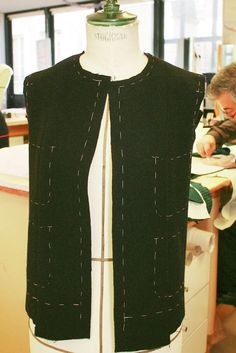 a mannequin wearing a black vest with white stitching