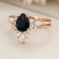 a black and white diamond ring sitting on top of a table next to a flower