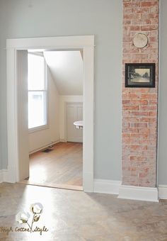 an empty room with a brick wall and clock on the side of the door way