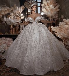 a woman in a white dress standing next to a chandelier