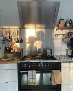 two people are kissing in the kitchen with their shadows on the stove and oven hood