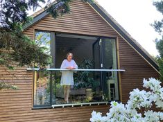 an older woman standing on the balcony of her house looking out onto the garden area