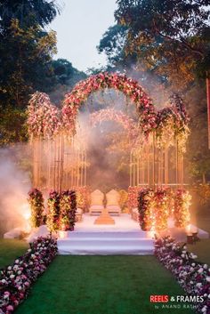 an outdoor ceremony setup with flowers and candles on the aisle, surrounded by greenery