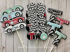 some cupcake toppers with cars on them are sitting next to each other in front of a wooden wall